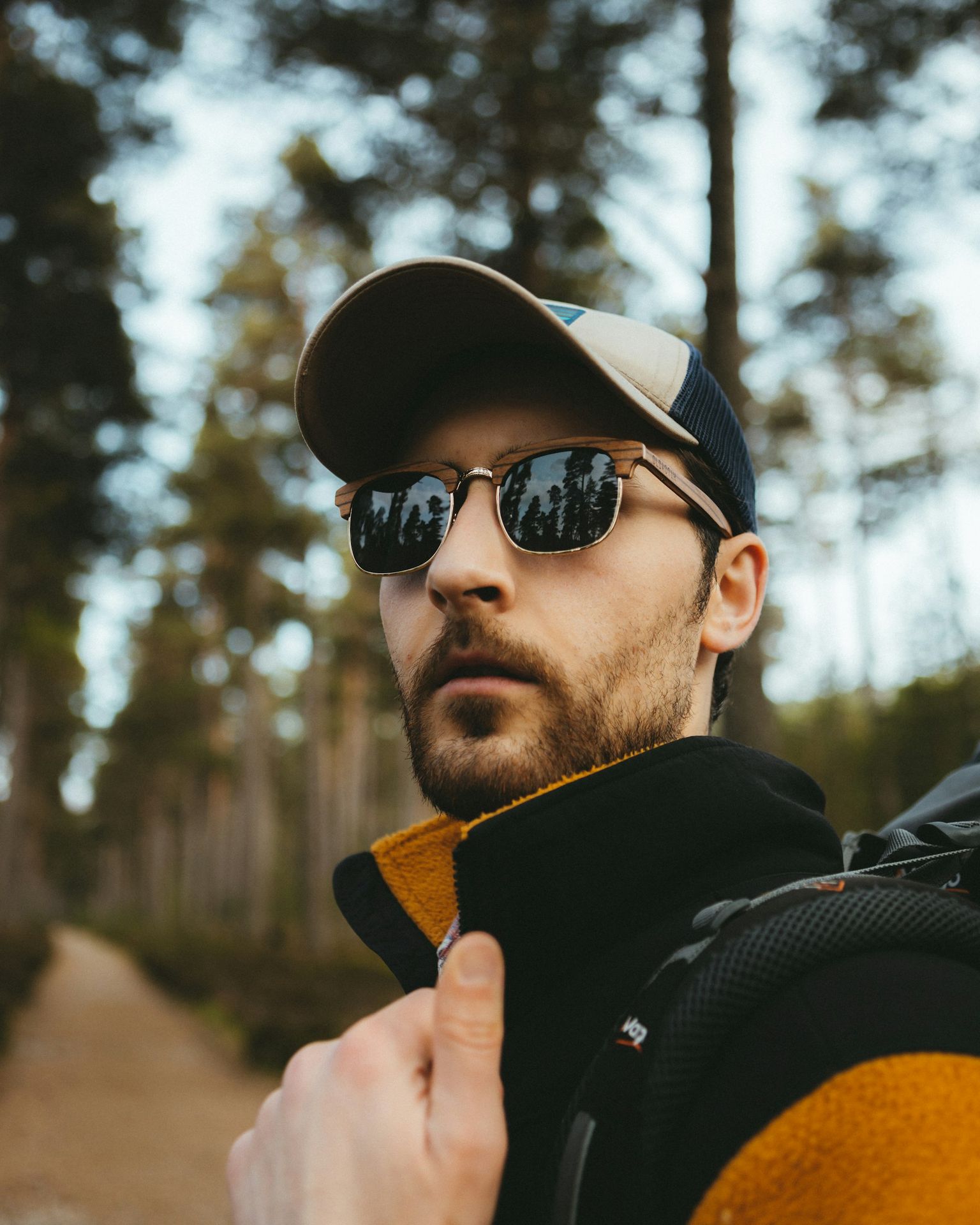 a man wearing sunglasses and a hat is standing in the woods